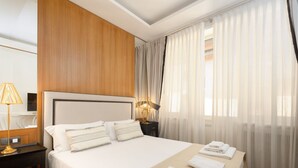 Ein Hotelzimmer mit einem großen Bett, einer Wand mit Holzverkleidung, einem Nachttisch mit Lampe und transparenten Vorhängen.