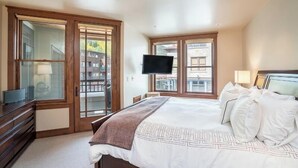 A bedroom with a large bed, a TV mounted on the wall, and a sliding glass door leading to a balcony. - 204 Ballard N-Curate Telluride, Town Center, Near Gondola, Parking, Partial AC (Telluride)