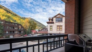 A balcony with a barbecue grill, overlooking a street with parked cars and buildings, and a mountain with autumn foliage. - 204 Ballard N-Curate Telluride, Town Center, Near Gondola, Parking, Partial AC (Telluride)
