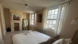 Ein Hotelzimmer mit einem großen Bett, einem Kamin, einer Heizung und zwei mit Vorhängen versehenen Fenstern.