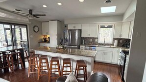 Una cocina moderna con una isla central, taburetes de bar y una zona de comedor con sofá.