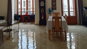 Una habitación amplia con una mesa de comedor, sillas, un reloj y ventanas grandes.