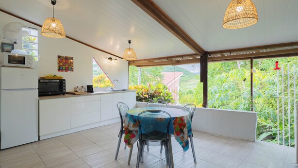 Una cocina moderna con armarios blancos, un microondas y un comedor con mesa y sillas.