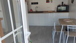 Una cocina moderna con armarios blancos, un microondas y un comedor con mesa y sillas.