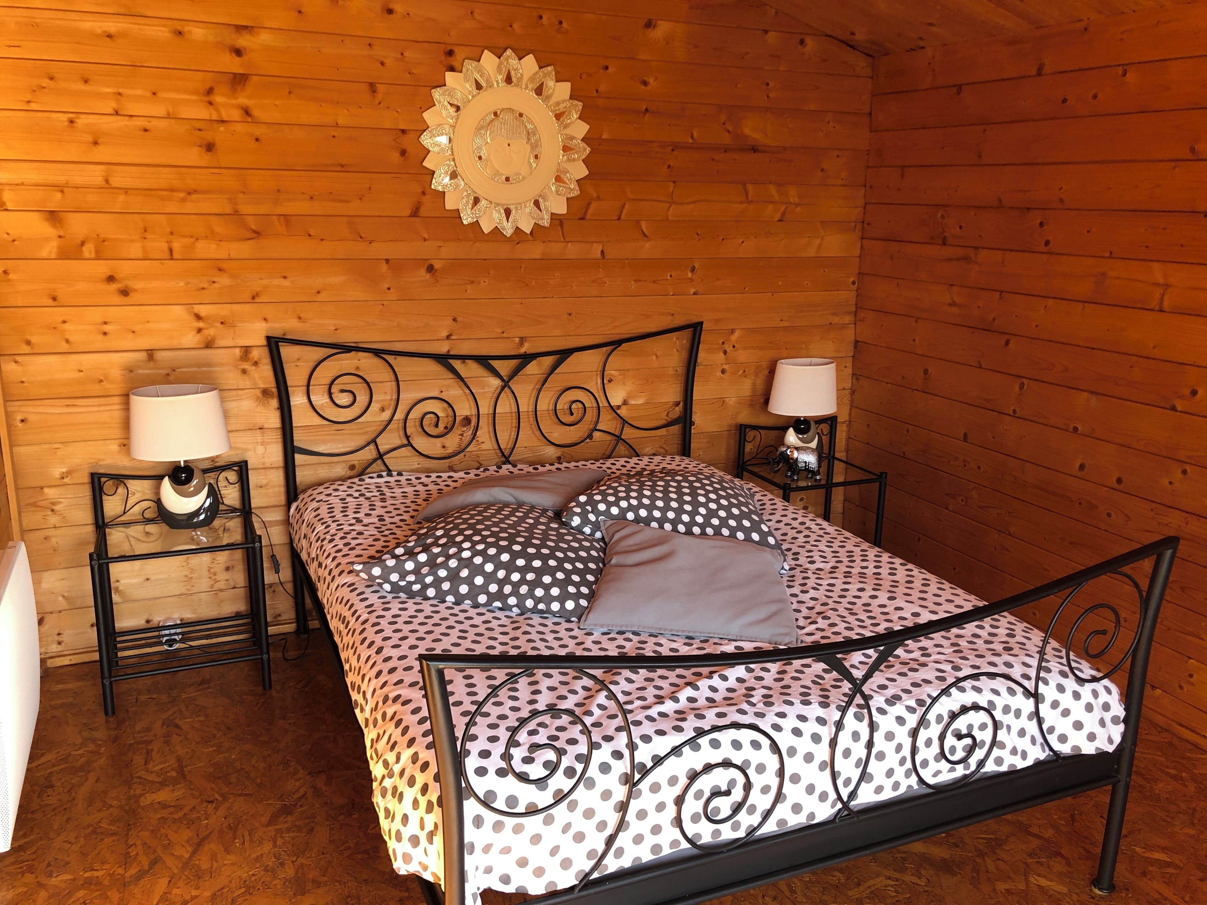 Un dormitorio de cabaña de madera con una cama, dos mesitas de noche y un adorno en la pared.