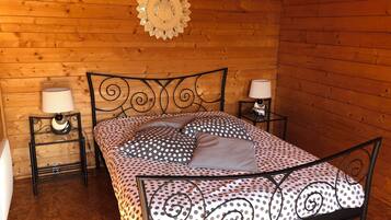 Un dormitorio de cabaña de madera con una cama, dos mesitas de noche y un adorno en la pared.