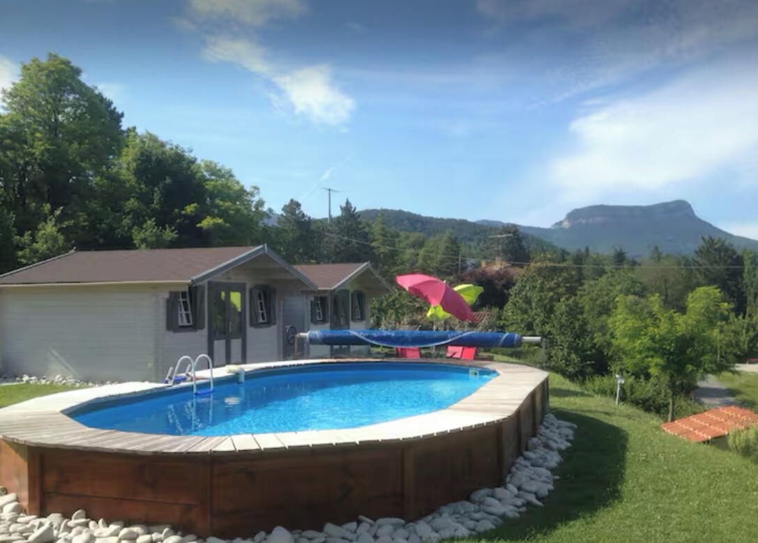 A swimming pool with a wooden deck, a slide, and a view of a mountain.