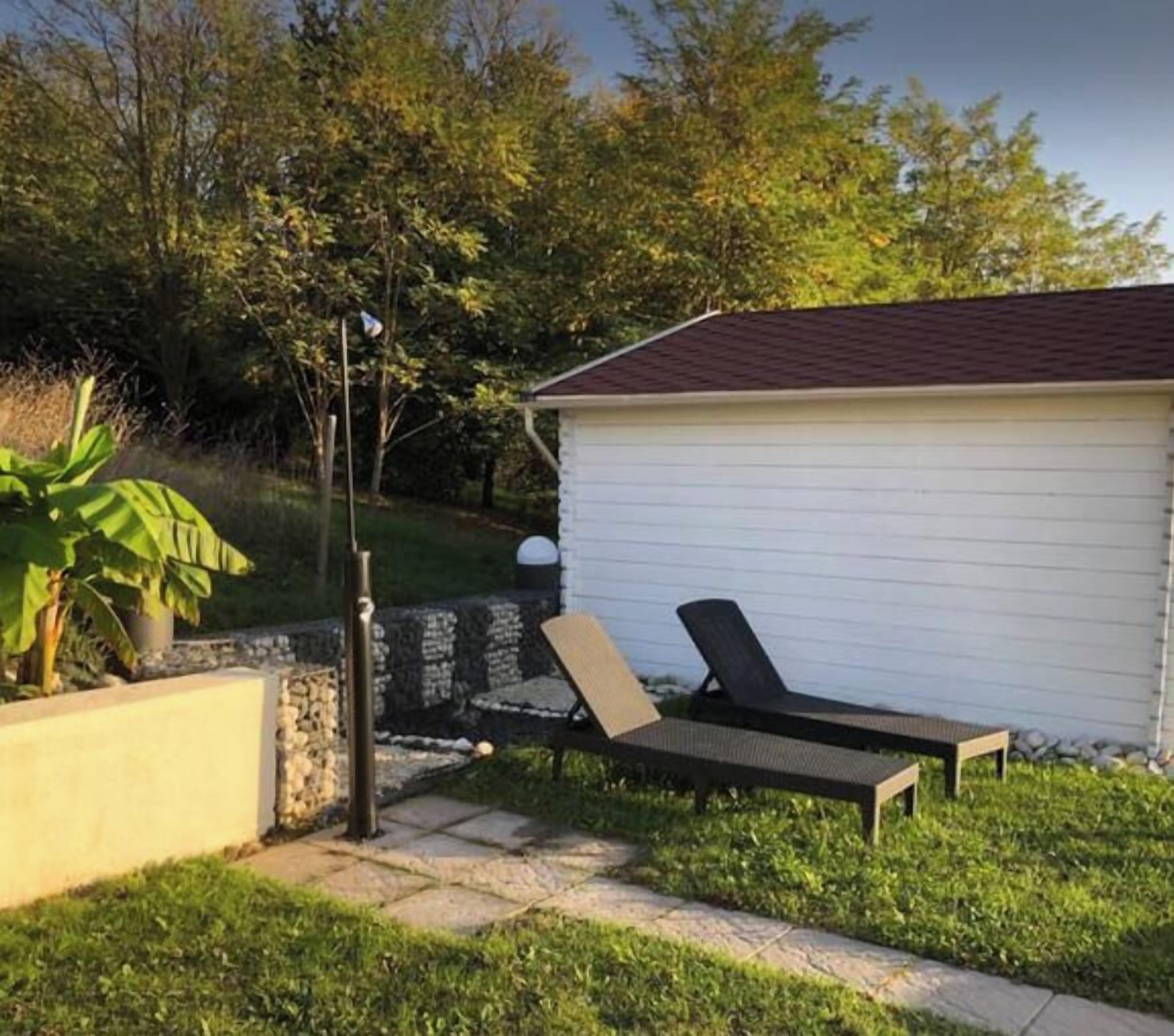 A backyard with a white shed, a stone wall, and a paved patio.