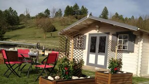 Een klein huisje met een terras, een eettafel en rode stoelen.