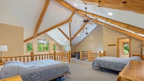 A spacious attic bedroom with two beds, wooden beams, and a view of greenery outside. - Kayaks, Indoor Pool, Hot Tub, Condo 841 (Crosslake)