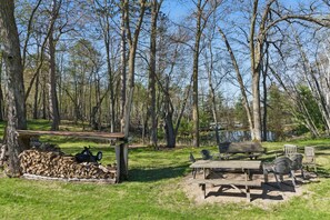 Ein Picknickplatz mit Bänken und Stühlen, umgeben von Bäumen und einem See.