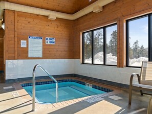 Una piscina interior con paredes de madera y ventanas grandes.