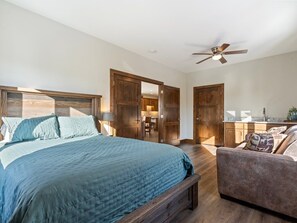 Ein Schlafzimmer mit einem großen Bett, einem Deckenventilator, Holzschränken und einer kleinen Sitzecke.