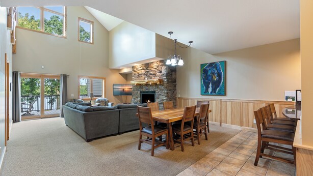 A spacious living area with a stone fireplace, a dining table with chairs, and a large sofa.