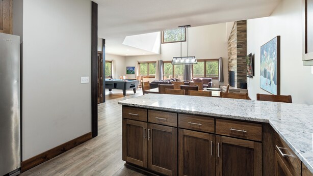A spacious kitchen with wooden cabinets, a marble countertop, and a view of the living area. - Luxury Townhome|Heart of Crosslake|Beach 832 (Crosslake)