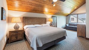 A bedroom with a wooden ceiling, a bed with a headboard, two bedside lamps, a nightstand, a window with a view, and a ceiling fan. - Luxury Townhome|Heart of Crosslake|Beach 832 (Crosslake)