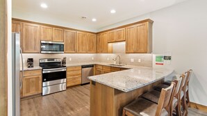 Una cocina moderna con armarios de madera, electrodomésticos de acero inoxidable y una isla con encimera de granito.