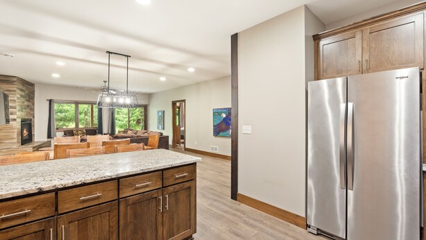 A modern kitchen with wooden cabinets, a stainless steel refrigerator, and a granite countertop.