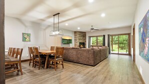 A spacious living area with a fireplace, wooden dining table, and comfortable seating.