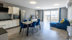 A modern apartment with a kitchen, dining area, and living room. It features a balcony with a view. - Beautifully Furnished 3 Bedroom Home in Qawra (Saint Paul's Bay)