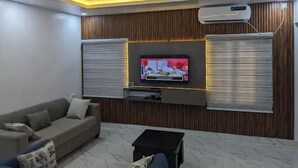 Una sala de estar moderna con un televisor de pantalla plana montado en una pared de madera, un sofá y una mesa de centro.