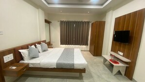 Une chambre d’hôtel moderne avec un grand lit, un téléviseur fixé au mur et une armoire.