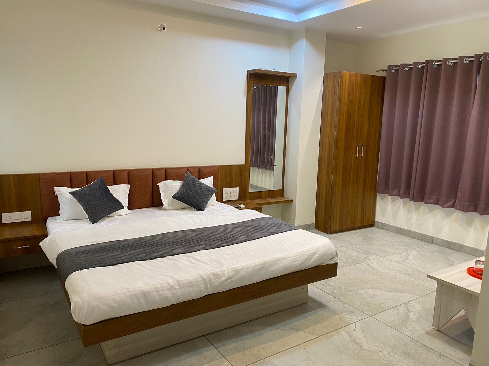 A neatly made bed with white and gray bedding, a wooden headboard, and a bedside table with a lamp.