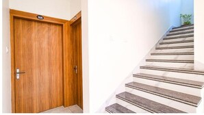 Une porte en bois avec une plaque portant un numéro et un escalier en marbre muni d’une main courante.