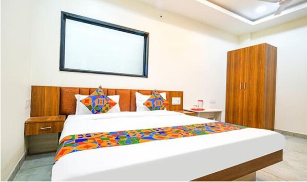 Habitación de hotel con cama, cabecero de madera, armario, mesita de noche y mesita auxiliar.