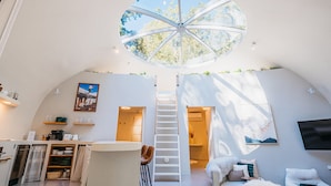 A spacious, modern interior with a central staircase, a dining area, and a cozy seating area.