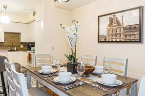 A dining area with a long table set for six, white chairs, and a framed picture on the wall. - Luxury 3BR/3BA•Air Hockey Lounge•Walkable Old City (Philadelphia)