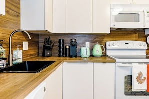 A kitchen with a sink, stove, microwave, coffee maker, and toaster. - Luxury 3BR/3BA•Air Hockey Lounge•Walkable Old City (Philadelphia)