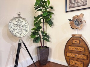 A wall-mounted clock, a potted plant, and a wooden cabinet with drawers. - Luxury 3BR/3BA•Air Hockey Lounge•Walkable Old City (Philadelphia)