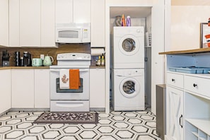 A compact kitchen with a microwave, oven, and stacked washer-dryer unit. - Luxury 3BR/3BA•Air Hockey Lounge•Walkable Old City (Philadelphia)