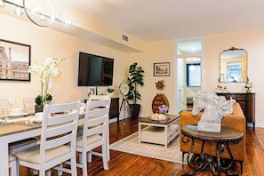 A dining area with a wooden table, white chairs, and a television on the wall. - Luxury 3BR/3BA•Air Hockey Lounge•Walkable Old City (Philadelphia)