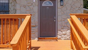 A stone building with a brown door and a wooden staircase leading up to it. - Glorius Amazing 2br/1ba Stay Near Lively Downtown! (San Antonio)