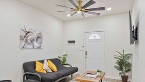 A modern living room with a black sofa, wooden coffee table, and a ceiling fan. - Glorius Amazing 2br/1ba Stay Near Lively Downtown! (San Antonio)