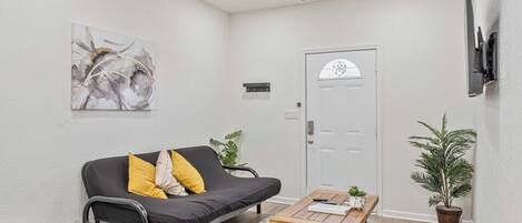 Un salon moderne avec un canapé noir, une table basse en bois et un ventilateur de plafond.