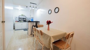 A dining area with a table, chairs, a vase with flowers, and a kitchen in the background. - 1 Bedroom Lumina Home Subdivision in Bacolod City (Bacolod)