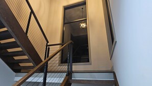 A staircase with wooden steps and metal railings, leading to a room with a large window and a chandelier. - Cruisehaus ATL- handicap accessible, 4 beds on main floor (Atlanta)