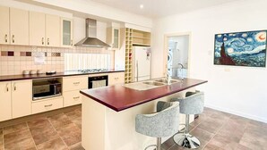 A modern kitchen with a central island, bar stools, and a painting on the wall.