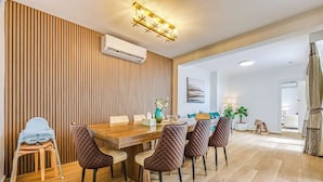 A dining area with a wooden wall, a table with chairs, and an air conditioning unit. - StayAU Pet-Friendly 4BR Retreat in Balwyn North (Balwyn North)
