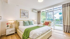A bedroom with a bed, bedside tables, a window, and a painting on the wall. - StayAU Pet-Friendly 4BR Retreat in Balwyn North (Balwyn North)