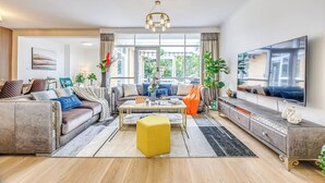 A modern living room with a sofa set, a coffee table, a TV, and a large window. - StayAU Pet-Friendly 4BR Retreat in Balwyn North (Balwyn North)