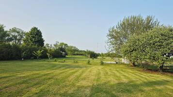 A well-maintained grassy field with trees and a clear sky.