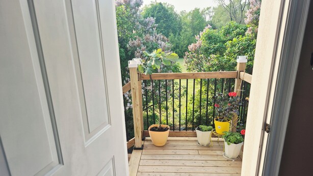 A wooden deck with potted plants and a welcome mat. - Issa place (Prince Edward)