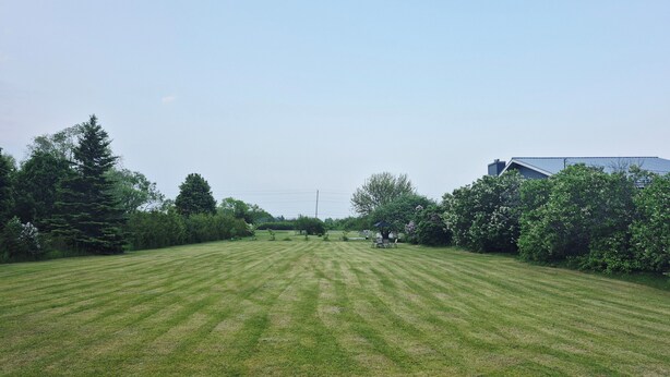 A well-maintained grassy field with a gazebo and a building in the background. - Issa place (Prince Edward)