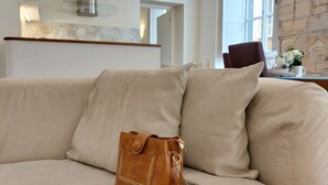 A beige sofa with a brown leather bag and a pair of glasses on it.