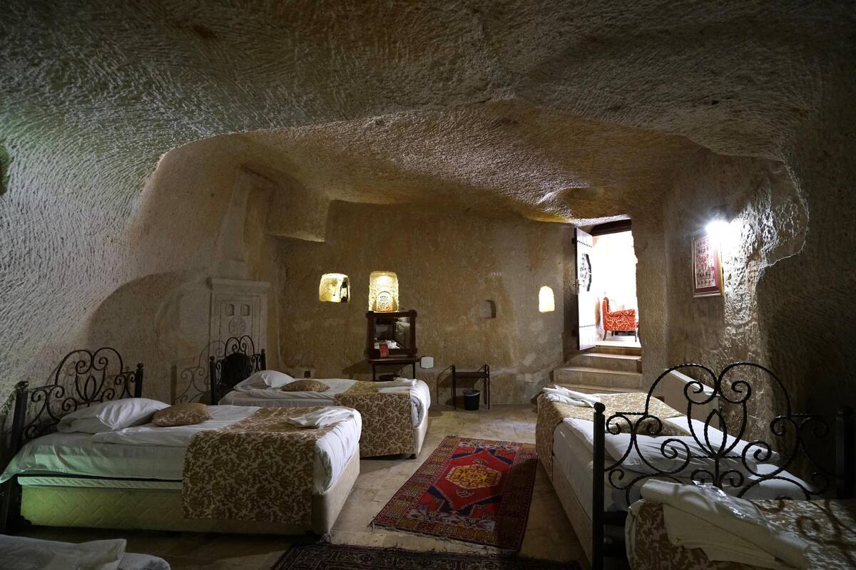 Ein höhlenartiges Zimmer mit drei Betten, einem kleinen Tisch und einem Stuhl.