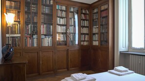 A library with wooden bookshelves, a lamp, and a bed with folded towels. - LuxRent Penthouse Crimea (Turin)
